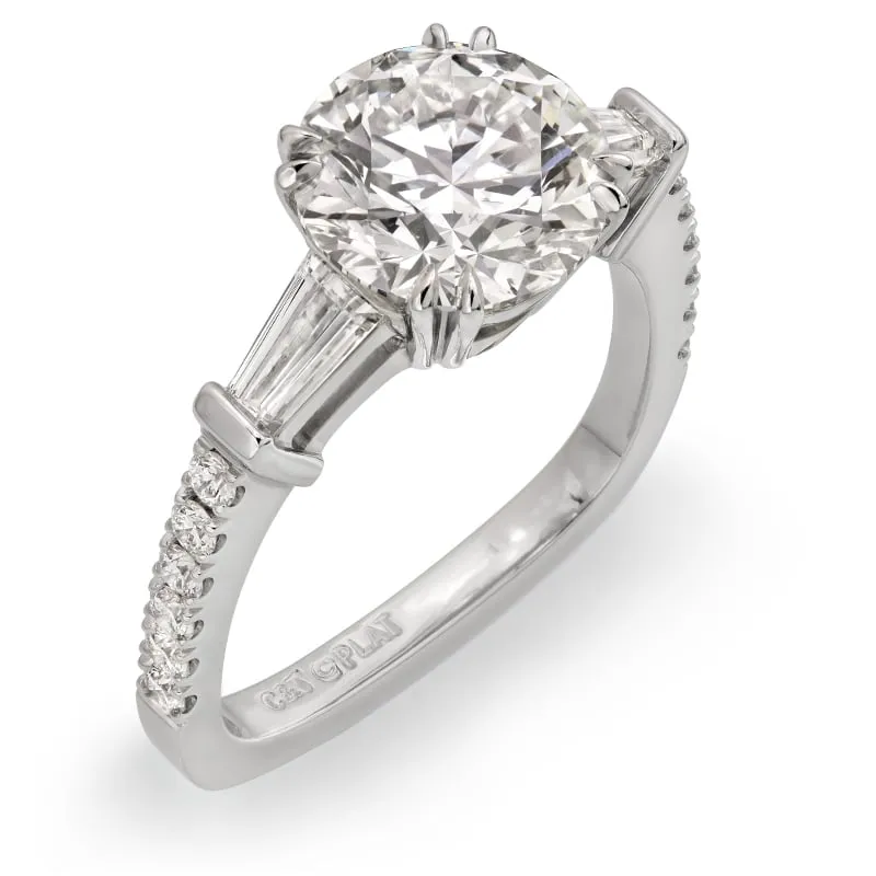 Platinum 3 Stone Engagement Ring featuring a 2.60ct Round Brilliant Cut Diamond center stone and tapered baguette accents, adorned with colorless round diamonds on the band, from Coffin & Trout's Classique Collection.