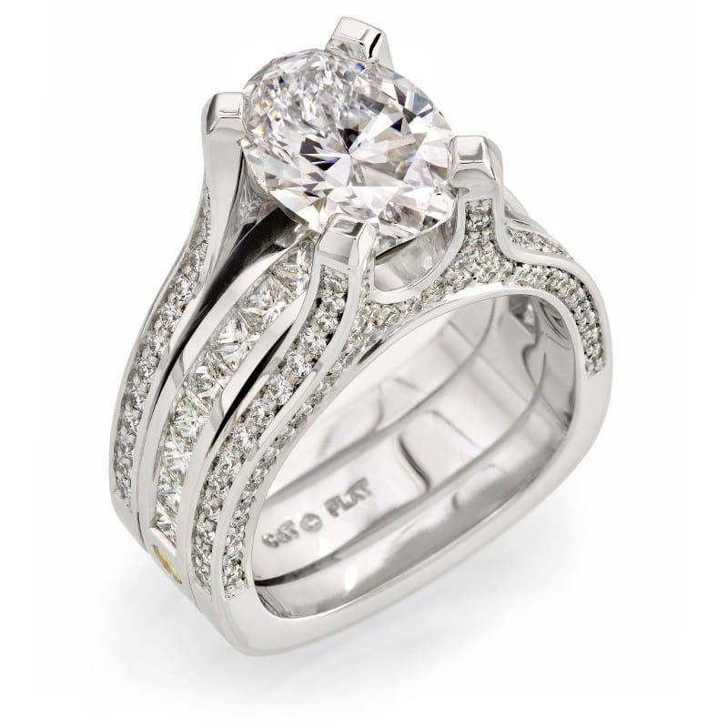 Platinum engagement ring featuring an oval diamond centerpiece and shimmering pavé-set diamonds along the band, symbolizing commitment and elegance in fine jewelry.